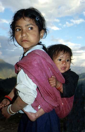 Young child carrying her baby brother in a traditional sling